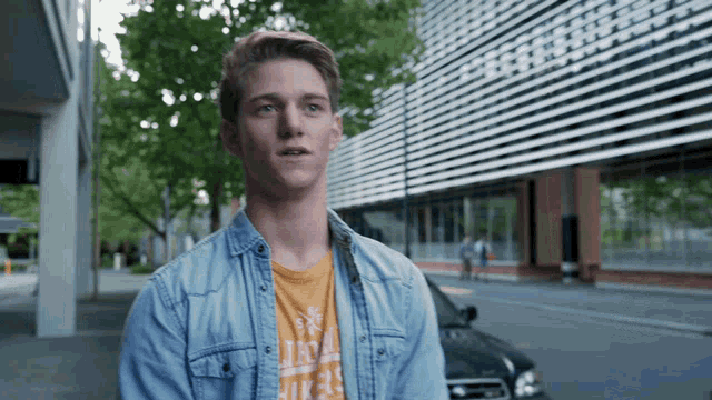 a young man wearing a denim shirt and an orange t-shirt that says california on it
