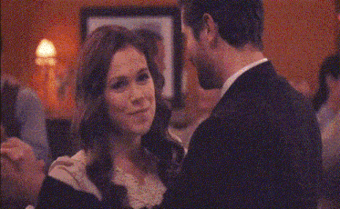 a woman in a white dress is looking at a man in a black suit .