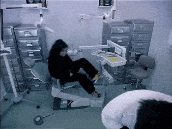 a woman sits in a dental chair while a man stands behind her