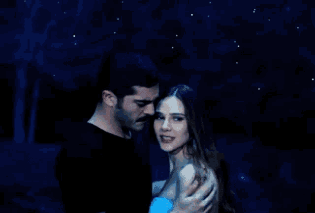 a man and woman are hugging each other in front of a blue sky