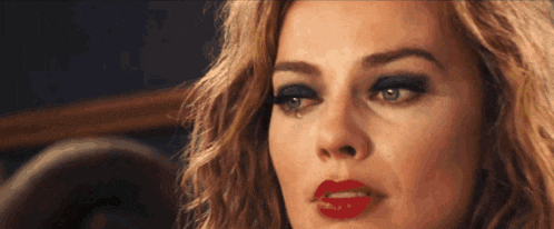 a close up of a woman 's face with red lipstick and black eyeshadow
