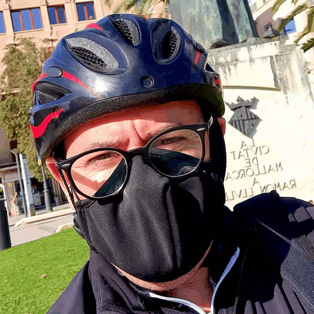 a man wearing a face mask and a helmet stands in front of a statue that says a tatuo