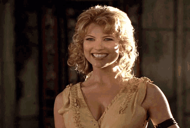 a woman with blonde hair and a plunging neckline smiles for the camera