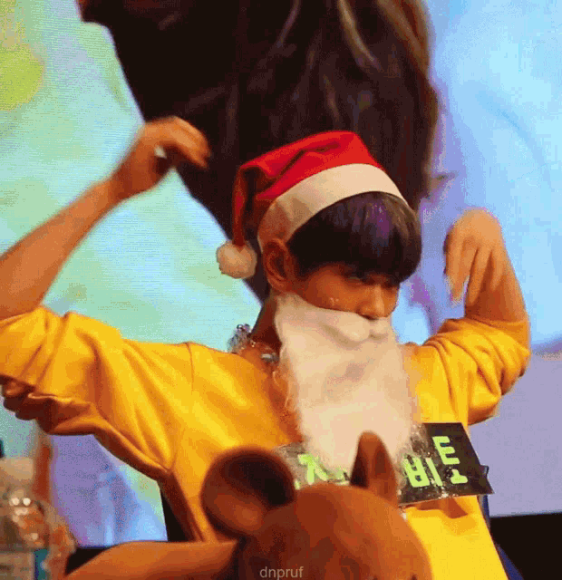 a person wearing a santa hat and a fake beard is holding a stuffed mouse