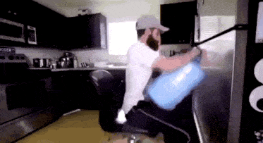a man sitting on a chair in a kitchen with a water bottle in his hand