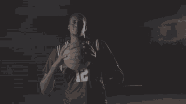 a man in a black shirt with the number 12 on it holds a basketball