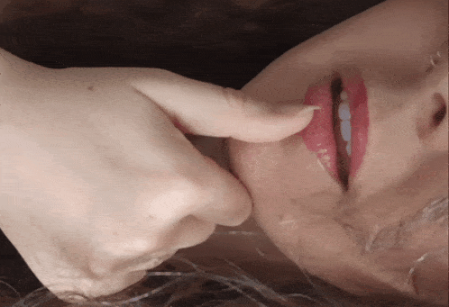 a close up of a woman 's face with her fingers on her mouth