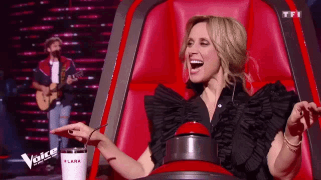 a woman sitting in a red chair with a cup that says lara on it