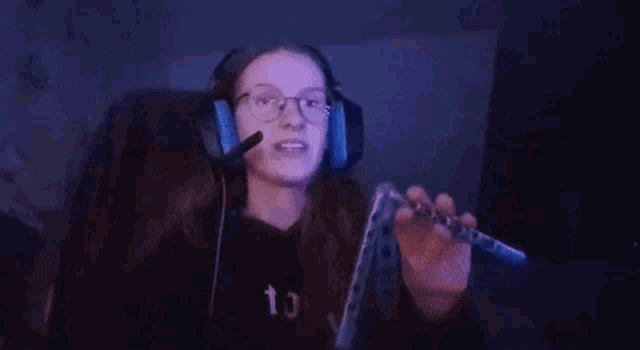 a woman wearing headphones and glasses is sitting in a chair with a microphone .