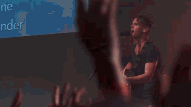 a crowd of people are raising their hands in the air