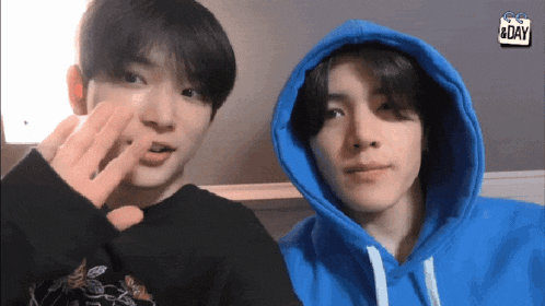 two young men wearing blue hoodies are standing next to each other with a sign that says go & day in the background