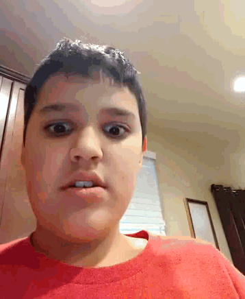 a young boy in a red shirt is making a surprised face