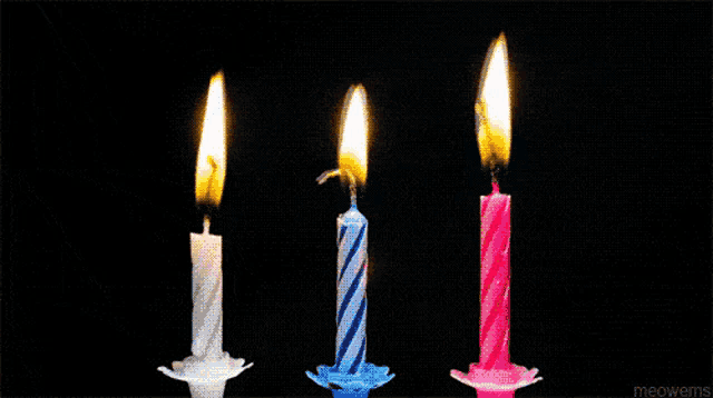 four birthday candles are lit up in a row on a dark background