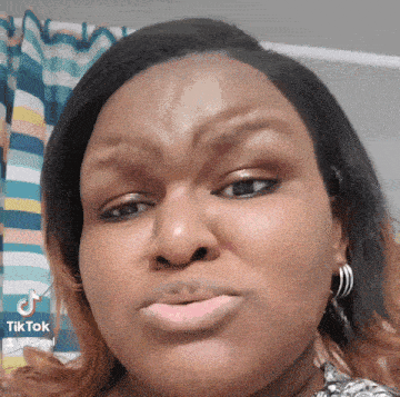 a close up of a woman 's face with a striped curtain in the background
