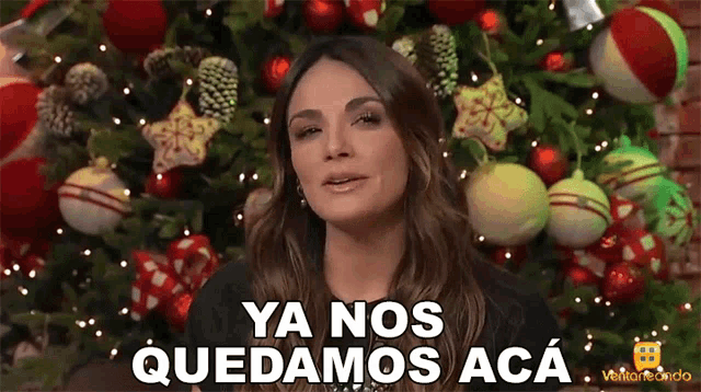 a woman in front of a christmas tree says ya nos quedamos aca in spanish