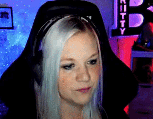 a woman with white hair is wearing headphones in front of a sign that says kitty on it