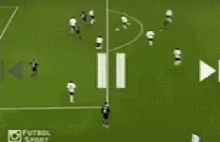 a soccer goalie stands in front of a soccer goal while a player runs towards him
