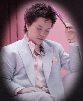a man in a light blue suit is holding a purple fan