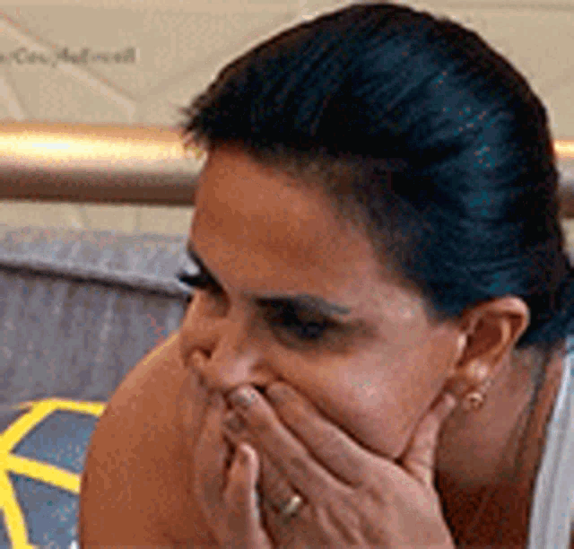 a close up of a woman covering her mouth with her hand