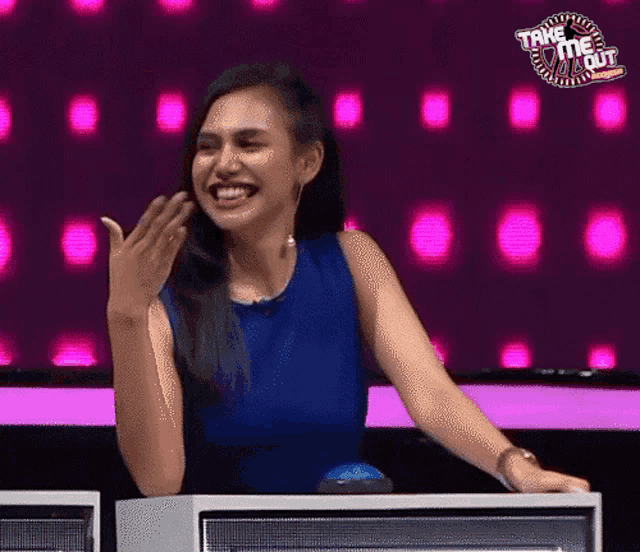 a woman in a blue dress is laughing in front of a sign that says " take me out "
