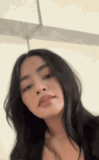 a woman with long dark hair is looking at the camera while wearing a black top .