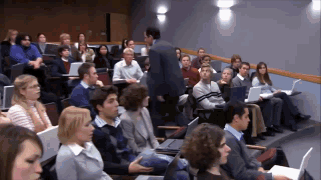 a man stands in front of a classroom full of students