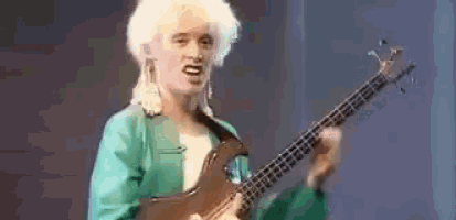 a woman in a green jacket is playing a bass guitar on stage .