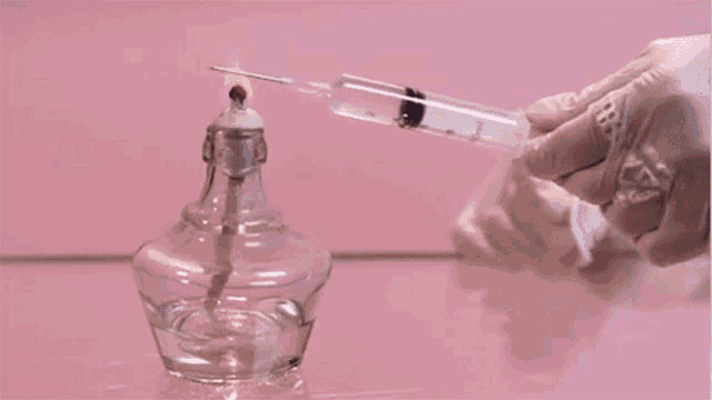 a person is holding a syringe in front of a candle holder