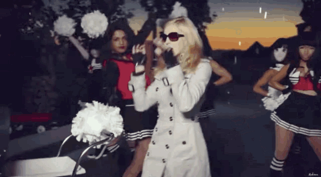 a woman in a trench coat is singing into a microphone
