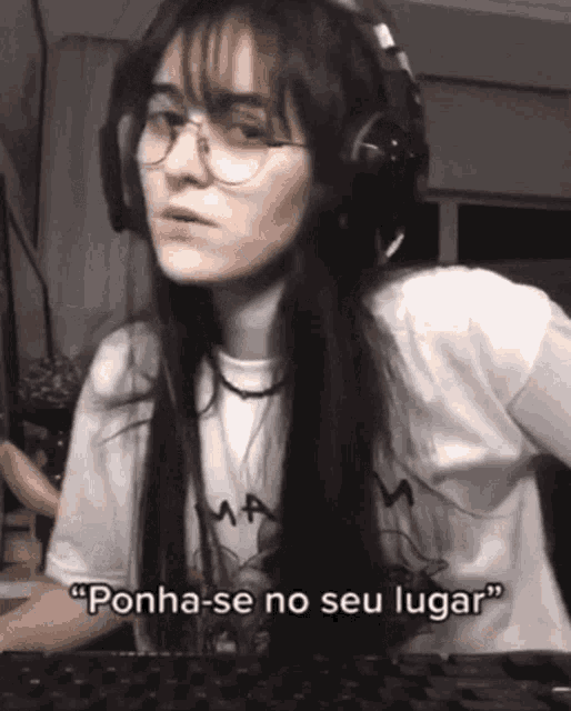 a woman wearing headphones and glasses says " ponha-se no seu lugar "