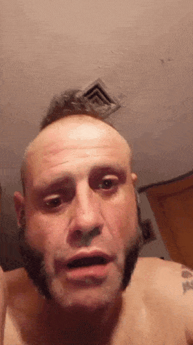 a shirtless man with a beard is making a funny face .