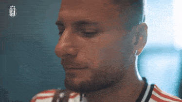 a close up of a man 's face with a beard and earring .