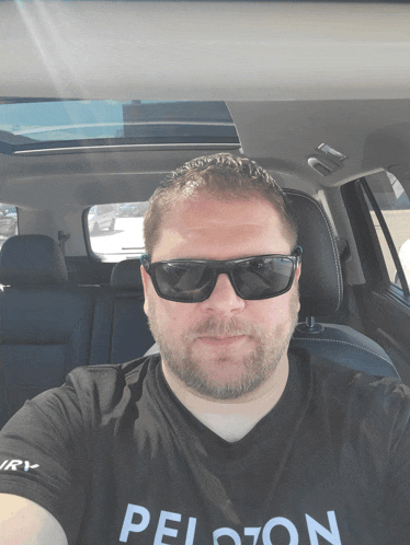a man wearing sunglasses and a shirt that says peloton takes a selfie