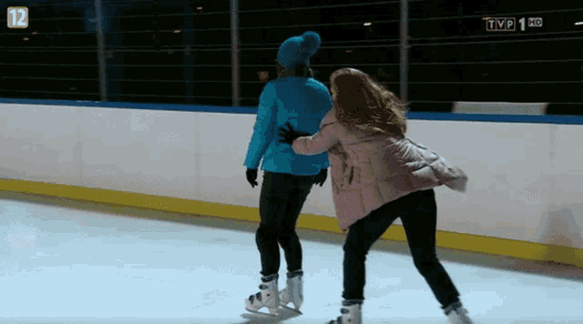 two women are ice skating in front of a tv screen that says tvp 1 hd on it
