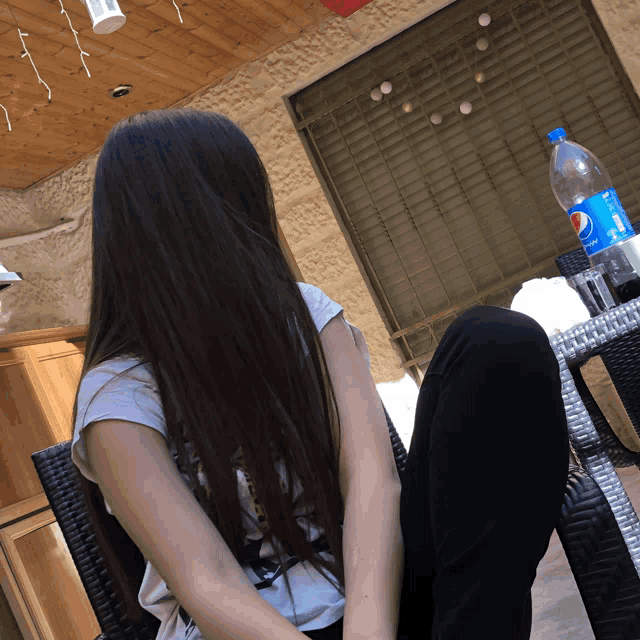 a bottle of pepsi sits on a table next to a woman