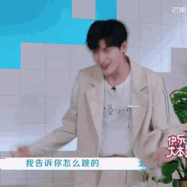 a man in a white jacket is dancing in front of a wall with chinese characters on it