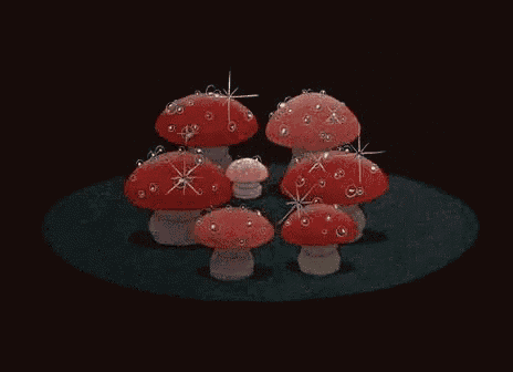 a group of red mushrooms with sparkles on them are sitting on a black surface .