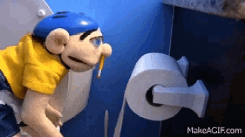 a puppet is looking at a roll of toilet paper with makeagif.com written on the bottom