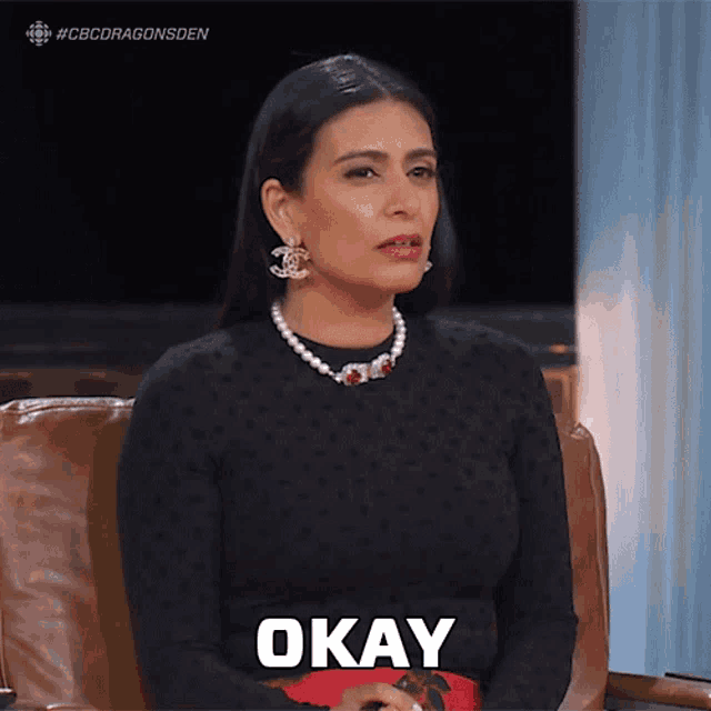 a woman is sitting in a chair with the word okay on her chest