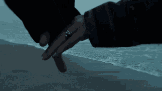 a man and woman holding hands on the beach