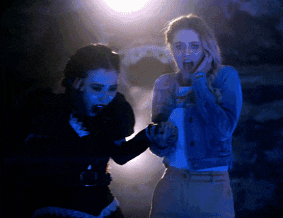 two women are standing in a dark room with one screaming