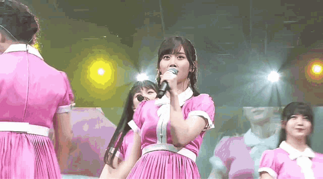 a woman in a pink dress is holding a microphone