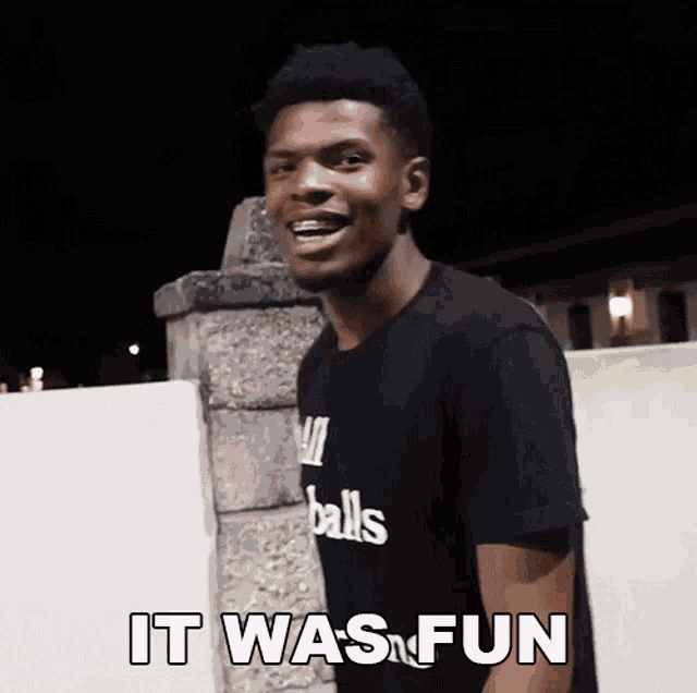 a young man wearing a black shirt that says balls on it