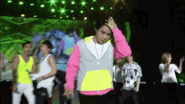 a man in a pink and yellow sweatshirt is holding his head