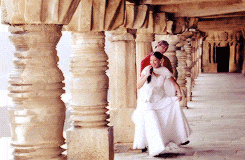 a man in a red shirt is holding a woman in a white dress