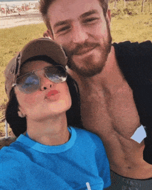 a man with a beard and a woman wearing sunglasses pose for a picture