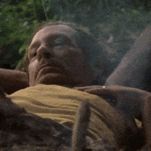 a man in a yellow shirt is laying on the ground with his hands on his chest