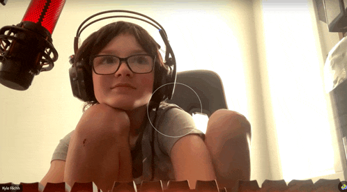 a young boy wearing headphones and glasses is sitting in front of a red microphone with the name myles higgins on the bottom