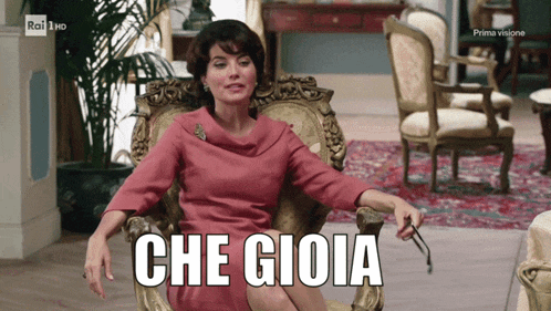 a woman in a pink dress is sitting in a chair with the words che gioia on the screen