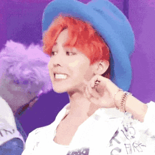 a man with red hair is wearing a blue hat and a white jacket .